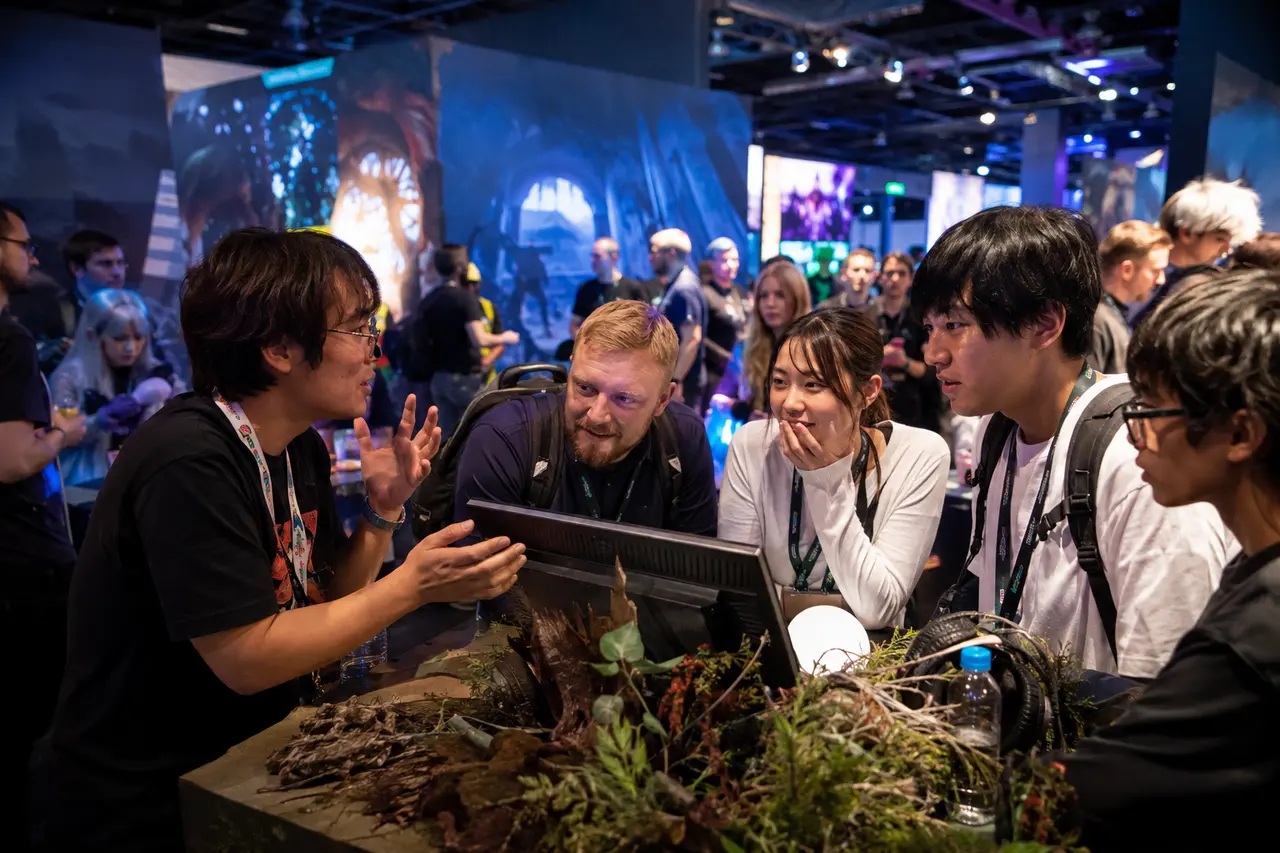 大規模なゲーム文化イベントで小規模開発者の作品を囲み、来場者が交流する様子