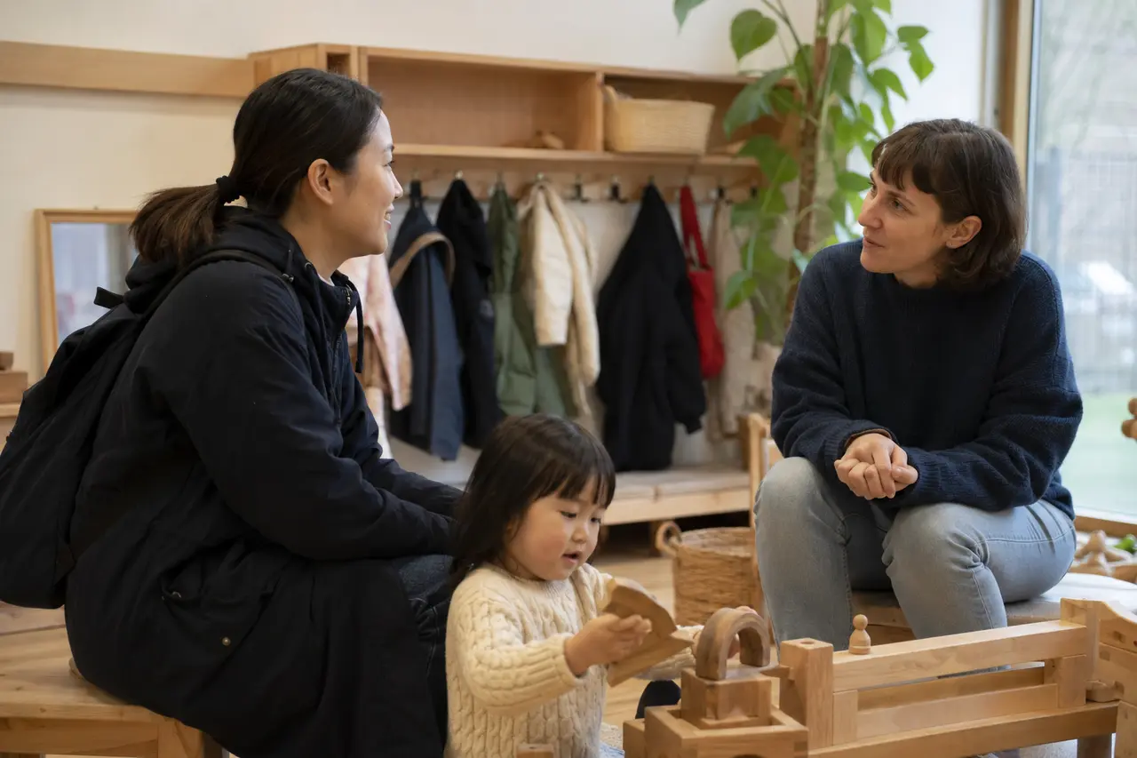 ドイツの保育先を初めて訪れ、保育者と子どもの様子を見る日本人家族